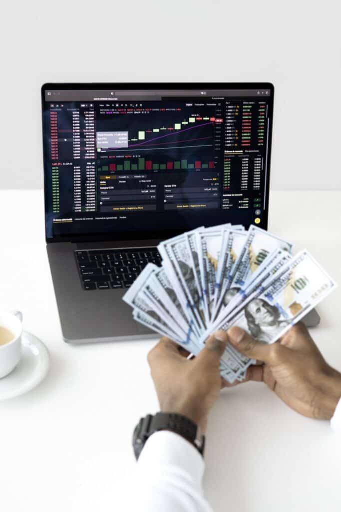 Investing trends on a laptop and a newcomer counting cash